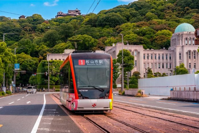 Iyotetsu tram in Matsuyama with the castle on the hill behind